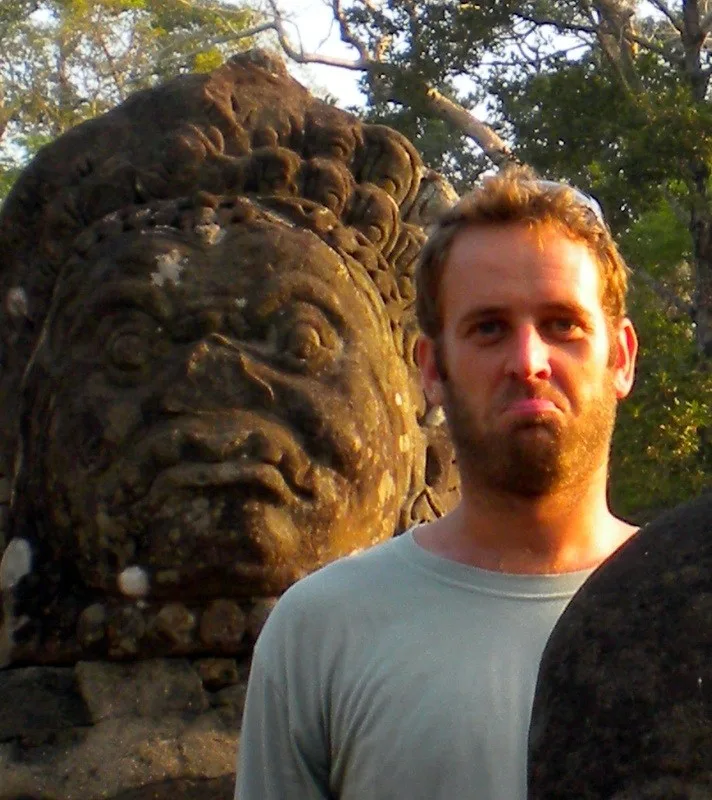 Brian posing with a statue of Angkor Wat, Cambodia
