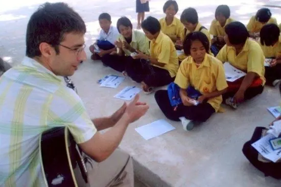 Alex playing his guitar with rapt students.