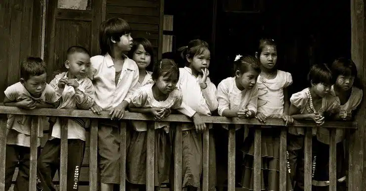 School children observe as Tyler navigates a plank joining two classrooms on Inle Lake.