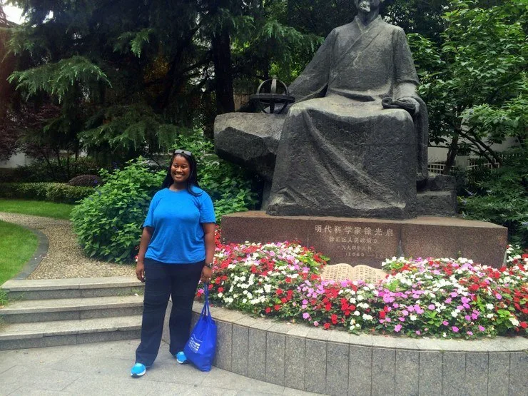 Candace in China with a larger-than-life statue of the famous scientist, farmer, and political figure, Xu Guangqi.